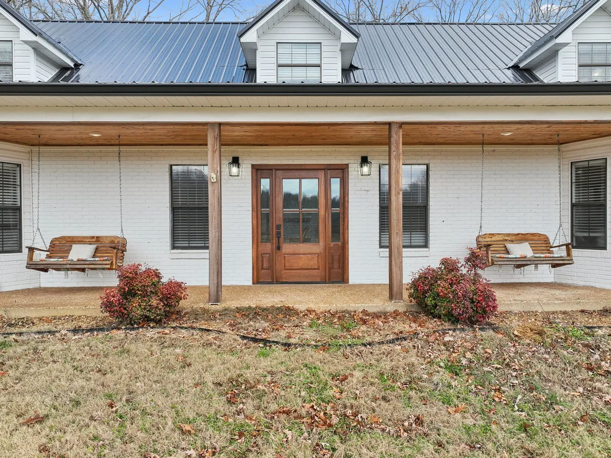 The photo showcases the inviting front porch, complete with swing seats, vibrant flower shrubs, and views of the sunrise. The porch looks ideal for relaxing after a day of outdoor adventure or enjoying the peaceful Tennessee mornings.