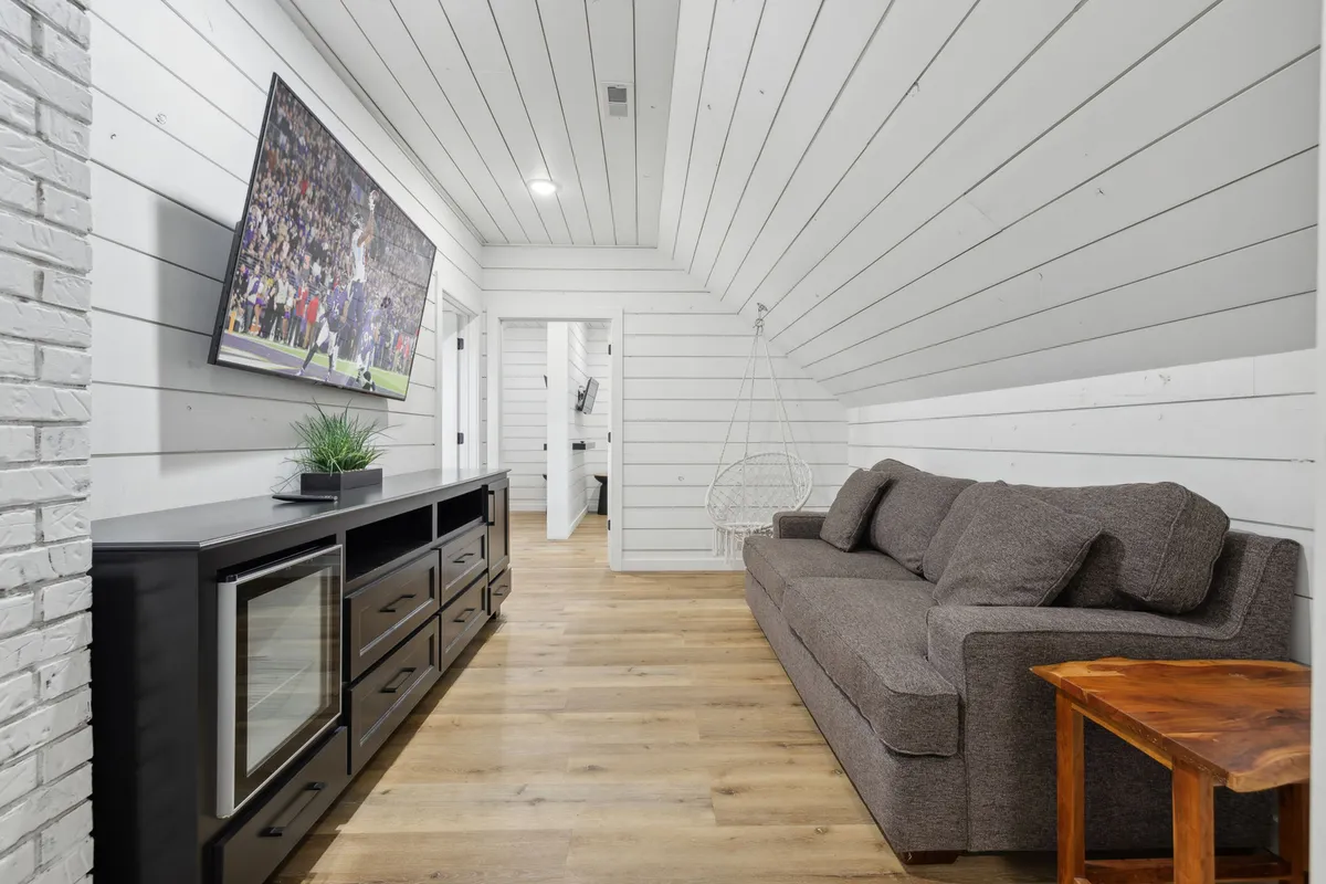 An inviting living space with a comfortable sofa, modern television, hanging chair, and central coffee table. The open layout encourages socializing, movie watching, and unwinding together, making it well-suited for family gatherings or group retreats.