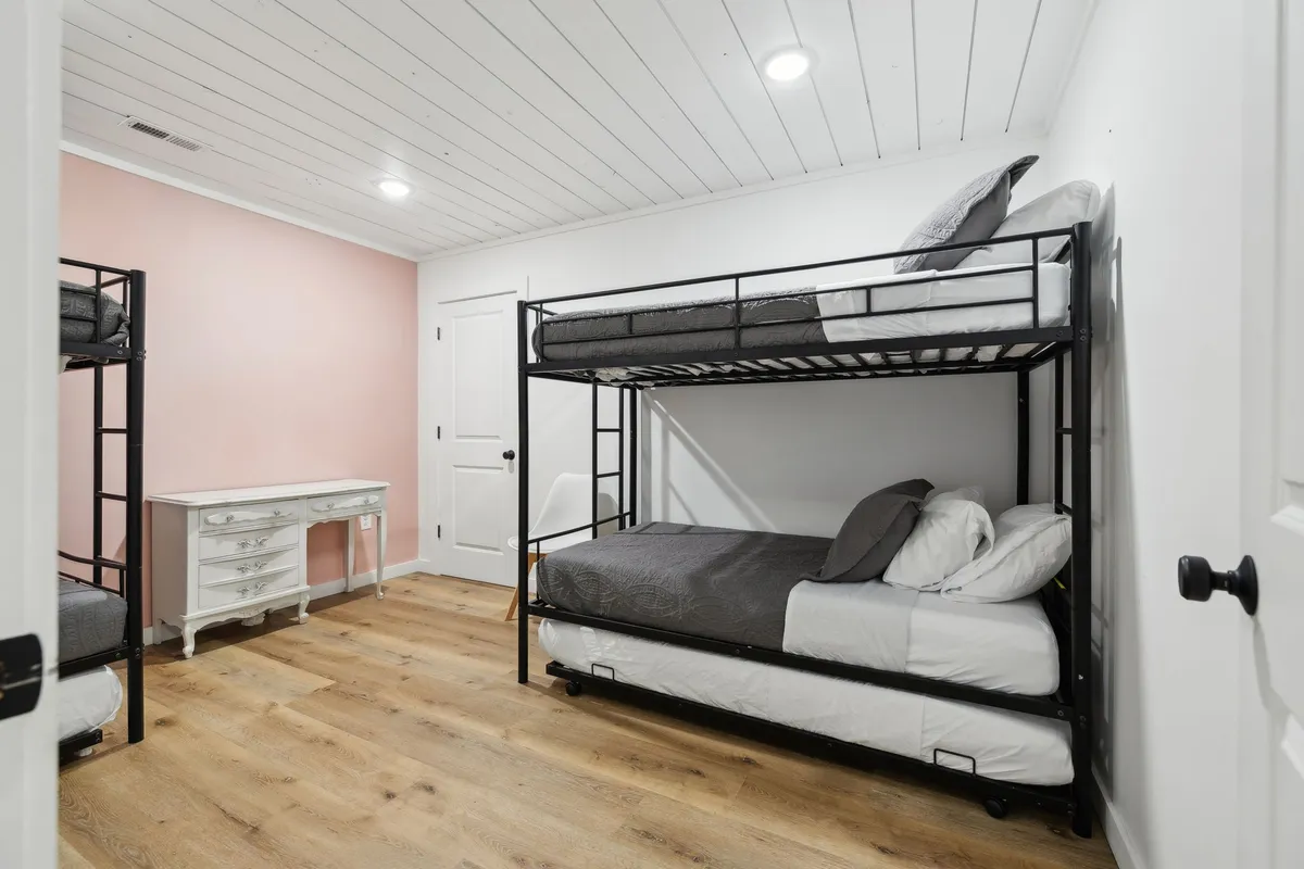 A playful bunk bed area with a white desk and pink accent wall, radiating a sense of fun and security for younger guests. The family-friendly design reflects consideration for children, making it easy for families to settle in.